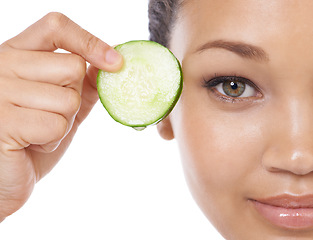 Image showing Skincare, cucumber and woman face or eye beauty for cosmetics, natural product and Vitamin C makeup in studio. Portrait of a young, happy model with green fruit and dermatology on a white background