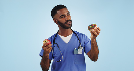 Image showing Doctor, man and studio for donut, apple and choice with thinking for healthcare by blue background. Medic, person or nutritionist with decision, cake and fruit with ideas for food, eating and diet