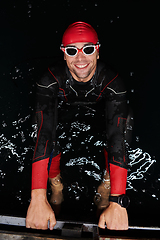 Image showing A determined professional triathlete undergoes rigorous night time training in cold waters, showcasing dedication and resilience in preparation for an upcoming triathlon swim competition