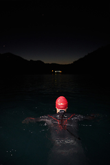 Image showing A determined professional triathlete undergoes rigorous night time training in cold waters, showcasing dedication and resilience in preparation for an upcoming triathlon swim competition