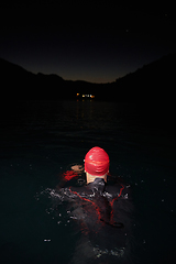 Image showing A determined professional triathlete undergoes rigorous night time training in cold waters, showcasing dedication and resilience in preparation for an upcoming triathlon swim competition