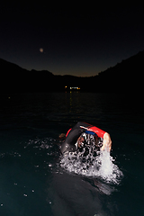 Image showing A determined professional triathlete undergoes rigorous night time training in cold waters, showcasing dedication and resilience in preparation for an upcoming triathlon swim competition