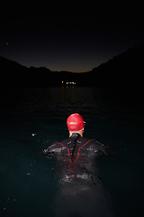 Image showing A determined professional triathlete undergoes rigorous night time training in cold waters, showcasing dedication and resilience in preparation for an upcoming triathlon swim competition