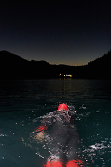 Image showing A determined professional triathlete undergoes rigorous night time training in cold waters, showcasing dedication and resilience in preparation for an upcoming triathlon swim competition