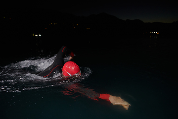 Image showing A determined professional triathlete undergoes rigorous night time training in cold waters, showcasing dedication and resilience in preparation for an upcoming triathlon swim competition