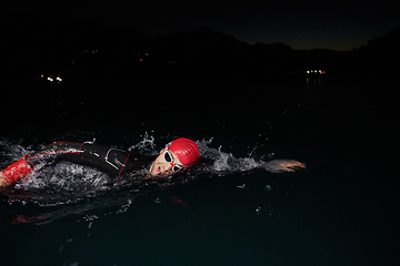 Image showing A determined professional triathlete undergoes rigorous night time training in cold waters, showcasing dedication and resilience in preparation for an upcoming triathlon swim competition