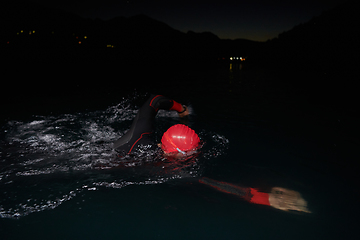 Image showing A determined professional triathlete undergoes rigorous night time training in cold waters, showcasing dedication and resilience in preparation for an upcoming triathlon swim competition