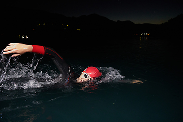 Image showing A determined professional triathlete undergoes rigorous night time training in cold waters, showcasing dedication and resilience in preparation for an upcoming triathlon swim competition