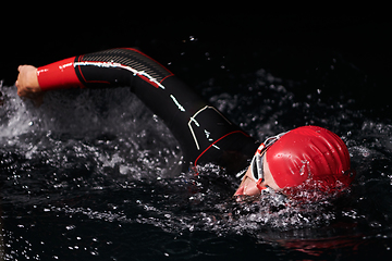 Image showing A determined professional triathlete undergoes rigorous night time training in cold waters, showcasing dedication and resilience in preparation for an upcoming triathlon swim competition