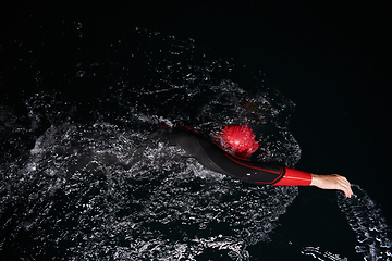 Image showing A determined professional triathlete undergoes rigorous night time training in cold waters, showcasing dedication and resilience in preparation for an upcoming triathlon swim competition