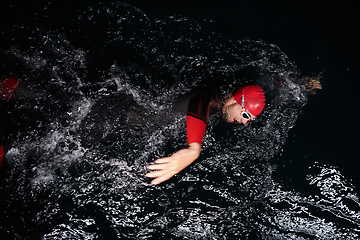 Image showing A determined professional triathlete undergoes rigorous night time training in cold waters, showcasing dedication and resilience in preparation for an upcoming triathlon swim competition