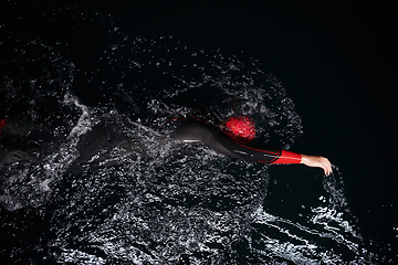 Image showing A determined professional triathlete undergoes rigorous night time training in cold waters, showcasing dedication and resilience in preparation for an upcoming triathlon swim competition