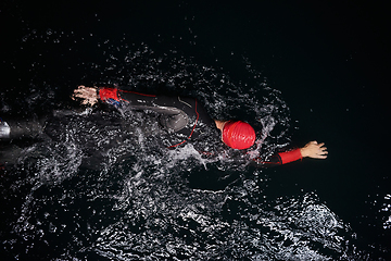 Image showing A determined professional triathlete undergoes rigorous night time training in cold waters, showcasing dedication and resilience in preparation for an upcoming triathlon swim competition