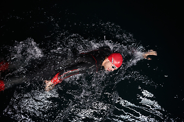 Image showing A determined professional triathlete undergoes rigorous night time training in cold waters, showcasing dedication and resilience in preparation for an upcoming triathlon swim competition