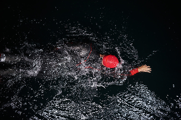 Image showing A determined professional triathlete undergoes rigorous night time training in cold waters, showcasing dedication and resilience in preparation for an upcoming triathlon swim competition