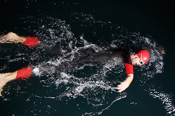 Image showing A determined professional triathlete undergoes rigorous night time training in cold waters, showcasing dedication and resilience in preparation for an upcoming triathlon swim competition