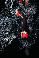 Image showing A determined professional triathlete undergoes rigorous night time training in cold waters, showcasing dedication and resilience in preparation for an upcoming triathlon swim competition