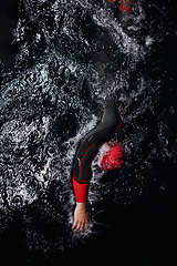 Image showing A determined professional triathlete undergoes rigorous night time training in cold waters, showcasing dedication and resilience in preparation for an upcoming triathlon swim competition