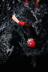 Image showing A determined professional triathlete undergoes rigorous night time training in cold waters, showcasing dedication and resilience in preparation for an upcoming triathlon swim competition