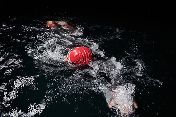 Image showing A determined professional triathlete undergoes rigorous night time training in cold waters, showcasing dedication and resilience in preparation for an upcoming triathlon swim competition