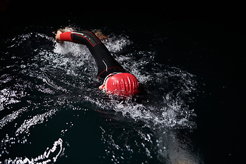 Image showing A determined professional triathlete undergoes rigorous night time training in cold waters, showcasing dedication and resilience in preparation for an upcoming triathlon swim competition