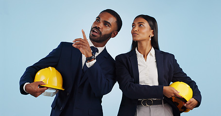 Image showing Business people, architect and pointing in vision for building or construction against a blue studio background. Man and woman in engineering or project plan with hard hat for safety on mockup space