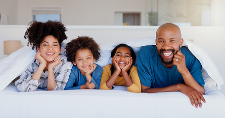 Image showing Happy, portrait and children with parents in bed of modern home for bonding together with love. Smile, fun and young interracial man and woman laying and relaxing with kids in bedroom of family house