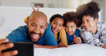 Image showing Selfie, smile and children with parents in bed of modern home for bonding together with teddy bear. Happy, fun and young interracial man and woman laying for rest with kids in bedroom of family house