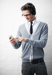 Image showing Man, headphones and listening to sound and phone for music by wall background, online and peace. Male person, smartphone and streaming radio or podcast, social media and hearing song on mobile app