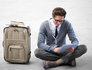 Image showing Business man, reading or luggage with tablet, floor and smile with app, flight or travel by wall background. Entrepreneur, person or employee with digital touchscreen, bag and happy for immigration