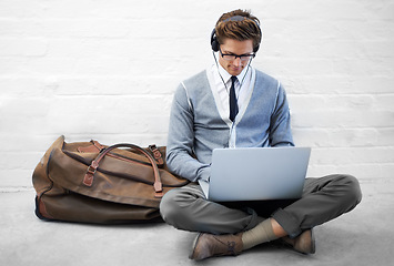 Image showing Business man, reading or luggage with laptop, floor and music with app, flight or travel by wall background. Entrepreneur, person or employee with headphones, computer or audio streaming subscription