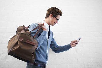 Image showing Business man, bag and phone by wall background with click for booking app, schedule and happy on travel. Entrepreneur, employee and smartphone for smile, reading and scroll on web for flight schedule