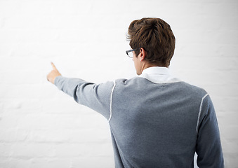 Image showing Man, back and pointing to mockup space by wall background, presentation and marketing or branding. Male person, advertising and product placement by backdrop, logo and sign or showing decision