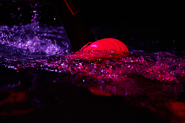 Image showing Authentic triathlete swimmer having a break during hard training on night neon gel light