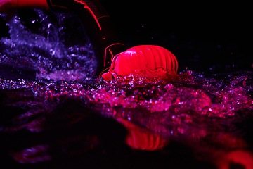 Image showing Authentic triathlete swimmer having a break during hard training on night neon gel light