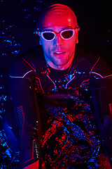 Image showing authentic triathlete swimmer having a break during hard training on night neon gel light