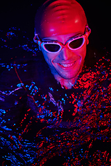 Image showing authentic triathlete swimmer having a break during hard training on night neon gel light