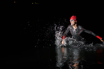 Image showing A determined professional triathlete undergoes rigorous night time training in cold waters, showcasing dedication and resilience in preparation for an upcoming triathlon swim competition