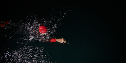 Image showing A determined professional triathlete undergoes rigorous night time training in cold waters, showcasing dedication and resilience in preparation for an upcoming triathlon swim competition