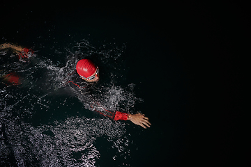 Image showing A determined professional triathlete undergoes rigorous night time training in cold waters, showcasing dedication and resilience in preparation for an upcoming triathlon swim competition