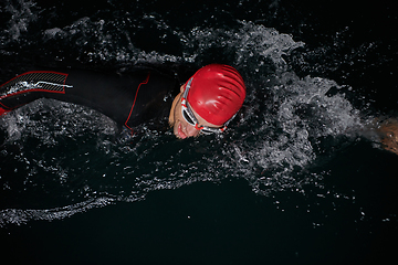 Image showing A determined professional triathlete undergoes rigorous night time training in cold waters, showcasing dedication and resilience in preparation for an upcoming triathlon swim competition