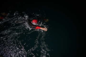 Image showing A determined professional triathlete undergoes rigorous night time training in cold waters, showcasing dedication and resilience in preparation for an upcoming triathlon swim competition