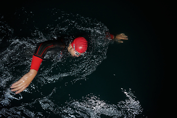 Image showing A determined professional triathlete undergoes rigorous night time training in cold waters, showcasing dedication and resilience in preparation for an upcoming triathlon swim competition