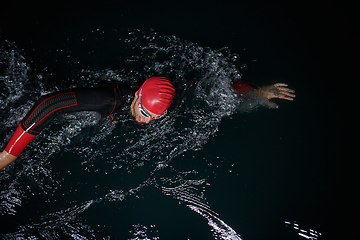 Image showing A determined professional triathlete undergoes rigorous night time training in cold waters, showcasing dedication and resilience in preparation for an upcoming triathlon swim competition