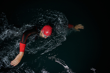 Image showing A determined professional triathlete undergoes rigorous night time training in cold waters, showcasing dedication and resilience in preparation for an upcoming triathlon swim competition