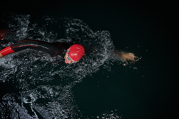 Image showing A determined professional triathlete undergoes rigorous night time training in cold waters, showcasing dedication and resilience in preparation for an upcoming triathlon swim competition