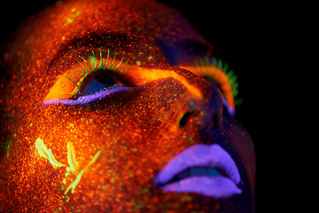 Image showing Art, woman with neon paint on face and beauty, closeup with bright lipstick and creative skincare on dark background. Orange glow, disco aesthetic and model in studio for creativity with makeup