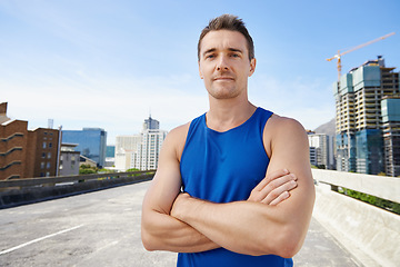 Image showing Man, arms crossed in city and fitness outdoor with workout, training and athlete in portrait for sports. Confidence, face and exercise on urban bridge, health and wellness with sportswear in Chicago