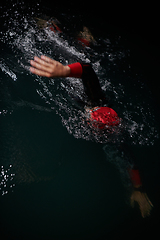 Image showing A determined professional triathlete undergoes rigorous night time training in cold waters, showcasing dedication and resilience in preparation for an upcoming triathlon swim competition