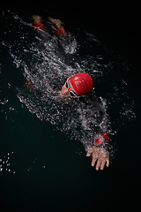 Image showing A determined professional triathlete undergoes rigorous night time training in cold waters, showcasing dedication and resilience in preparation for an upcoming triathlon swim competition